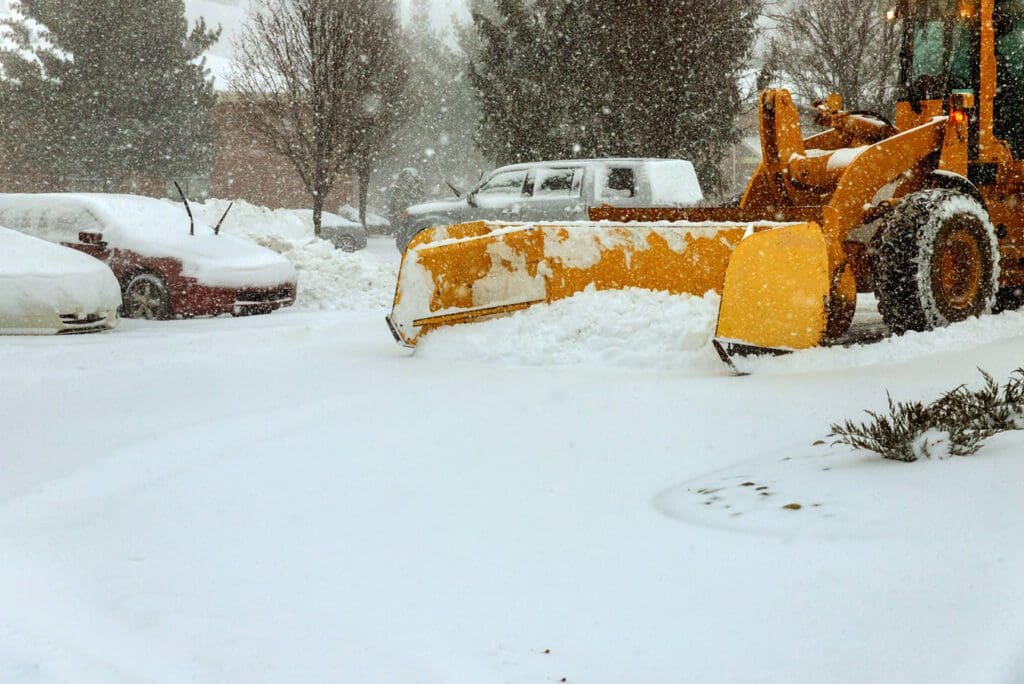 Clearing snow on the road in the parking for cars