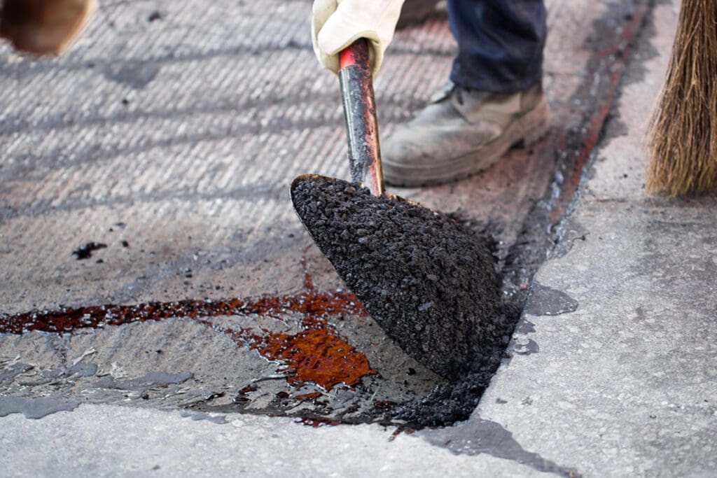 Shoveling asphalt onto a crack or repair and patching