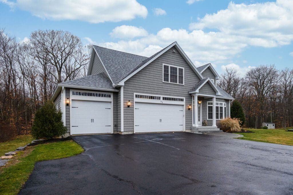 A gray-walled suburban house with wide asphalt driveway